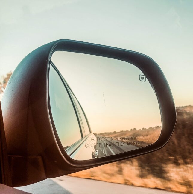 side mirror of car on road trip