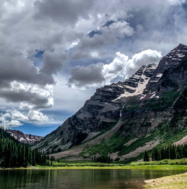 mountain and lake with clouds and trees and grass and rocks and sky