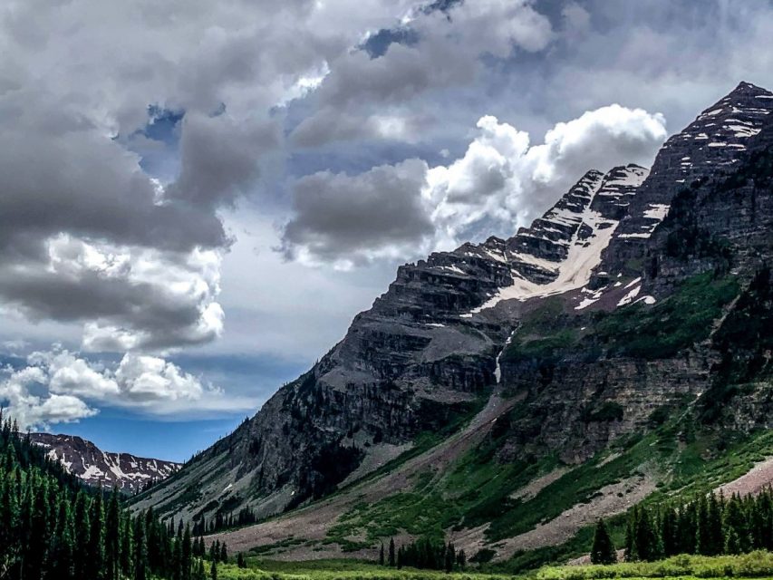 mountain and lake with clouds and trees and grass and rocks and sky