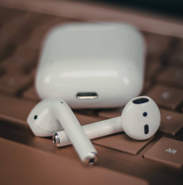 AirPods with AirPods Case on Laptop keyboard with laptop trackpad and screen